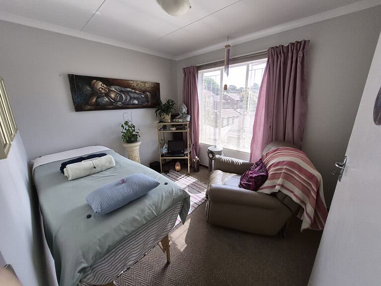 Comfortable therapy room with bed, armchair, and relaxing decor in Pretoria.
